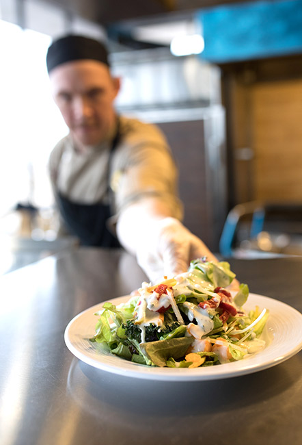 Chef handing salad forward