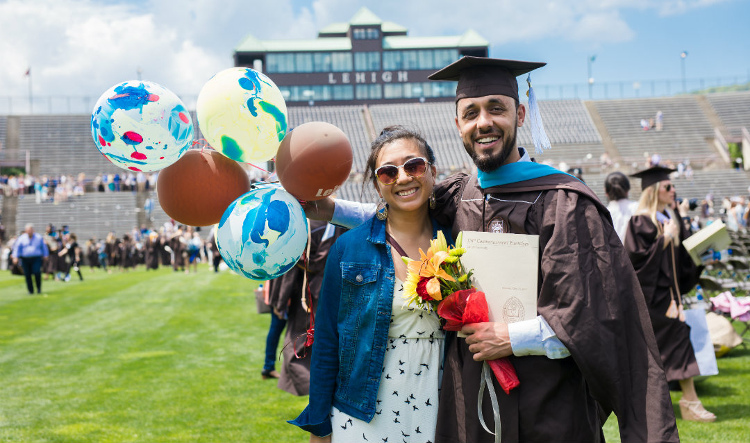 Graduate Kalim Abed stands with woman and holds balloons at Lehigh University commencement