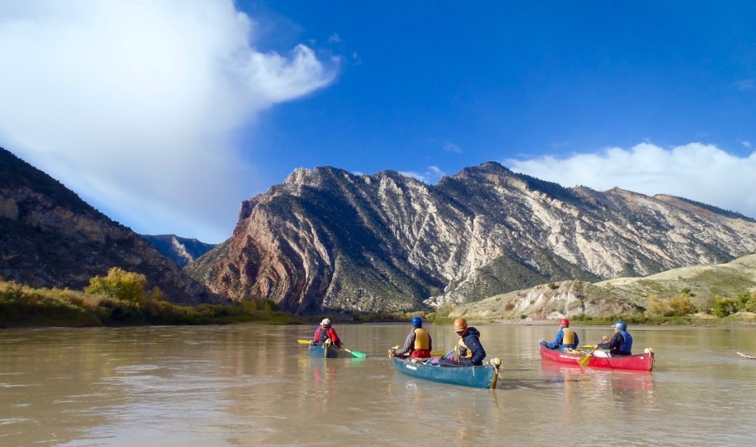 Group of people canoeing in Utah with view of mountains in the distance. 