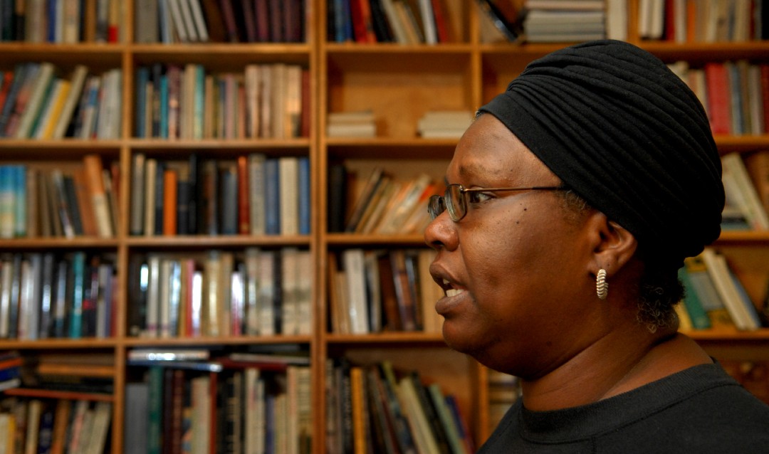 Image of writer Gloria Naylor in profile in front of shelves of books