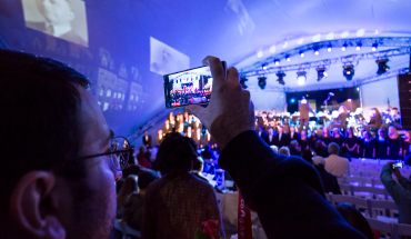 Man using his phone to record an event on a stage
