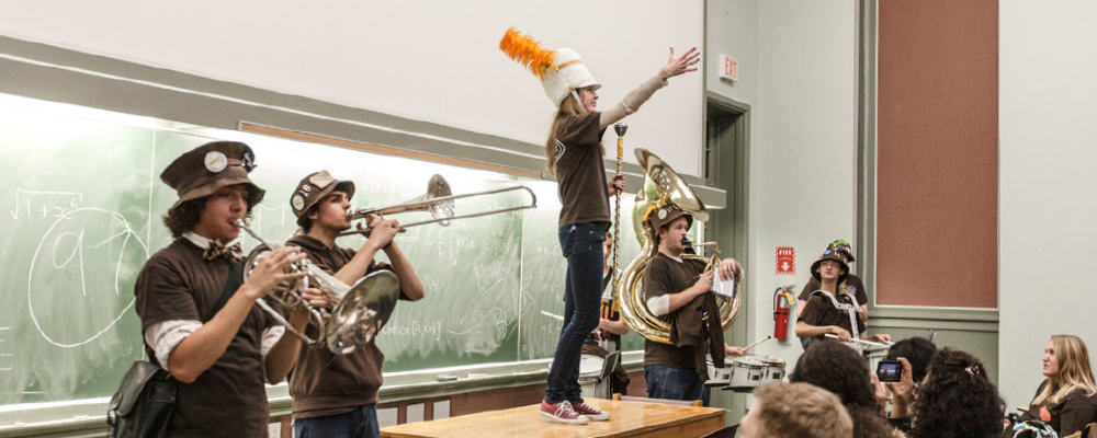 Members of the marching band playing at the front of a classroom