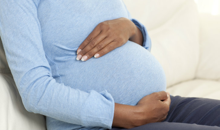 Unidentifiable pregnant woman with hands over belly