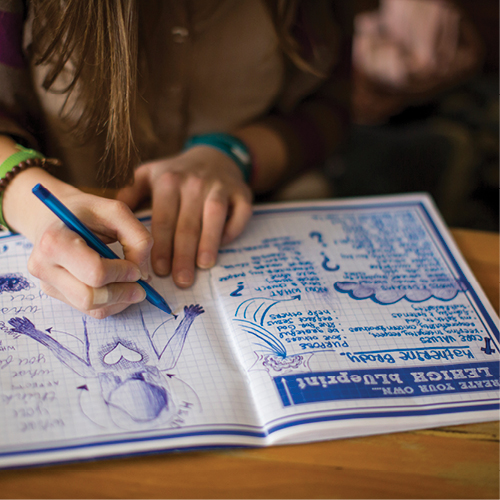 Hands writing in a Blueprint notebook