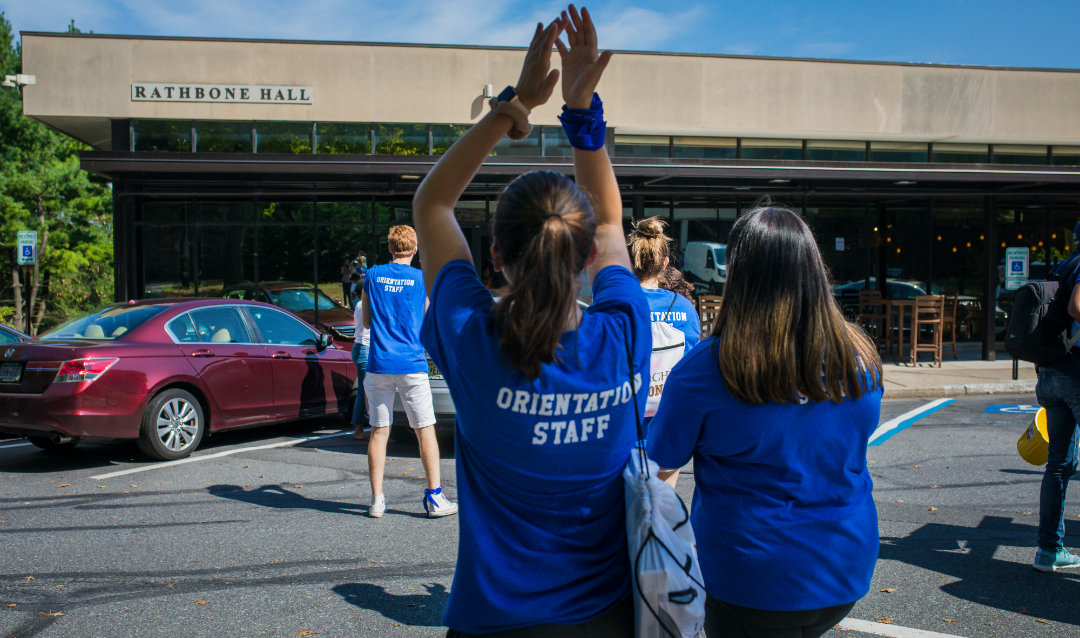 MOOV volunteers cheer as they approach a vehicle to unpack an arriving first-year student
