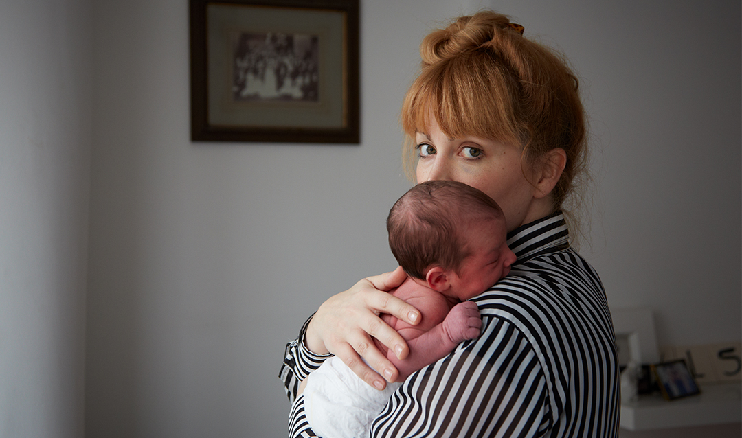 Image of woman staring at camera, holding infant