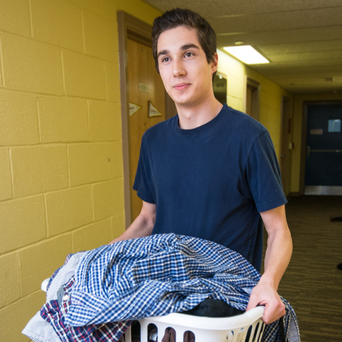 Student carrying laundry basket full of clothes