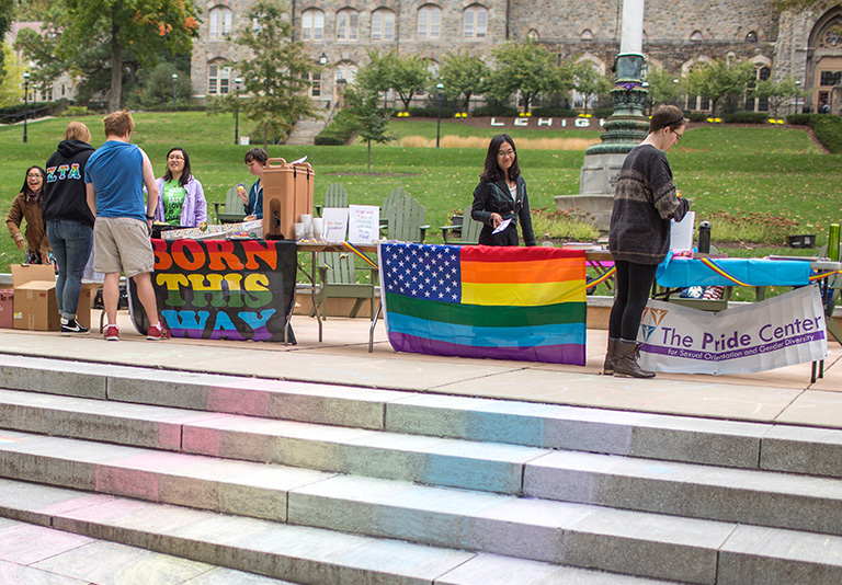 students next to tables with rainbow flags
