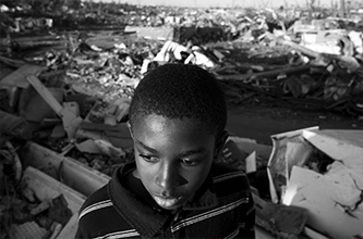 A young boy stands in front of debris following a tornado