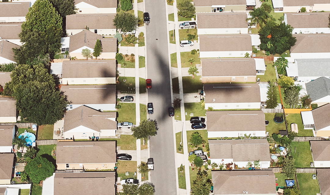 Aerial image of rooftops of houses with shadow of airplane