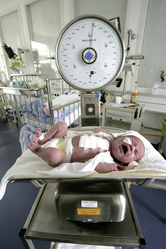 Image of newborn baby being weighed on scale after birth