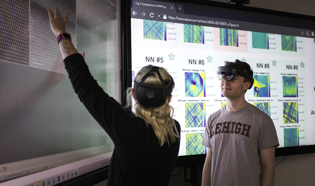 Two Lehigh students wear VR headsets in front of a large touchscreen