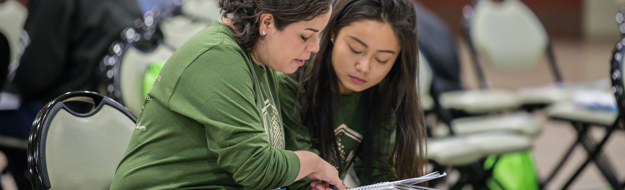 Two female students looking at a notebook together