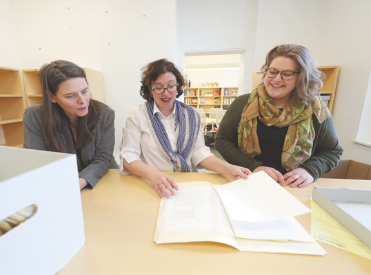 Professors and a research assistant examine documents