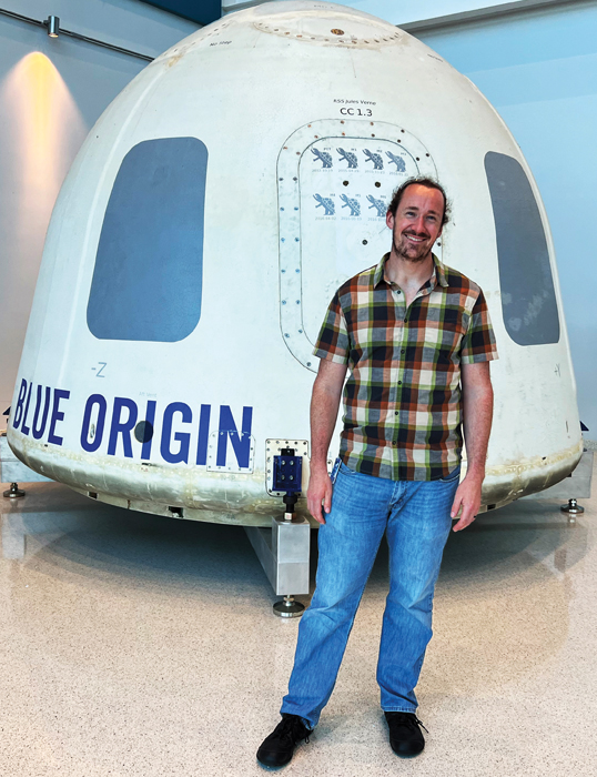 Alex Weldon ’14 Ph.D. in front of Blue Origin capsule