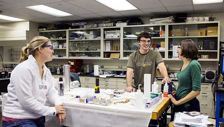 Two female students and one male students talking in a lab