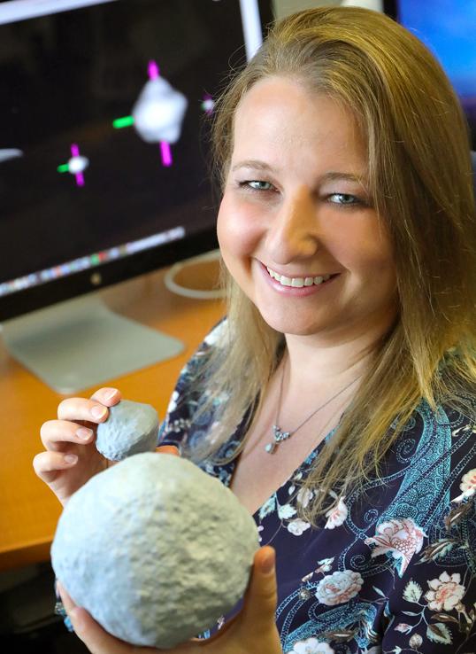 Tracy Becker ’09 holding models of planetary and celestial bodies