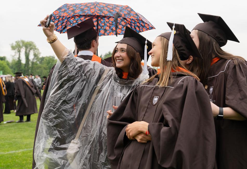 graduates pose for photos in the rain
