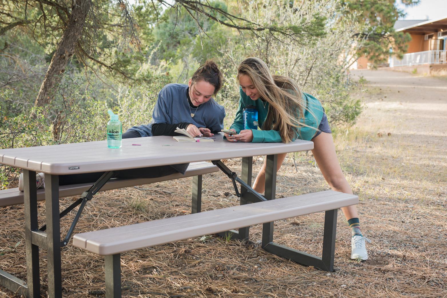 Two female students at a picnic table