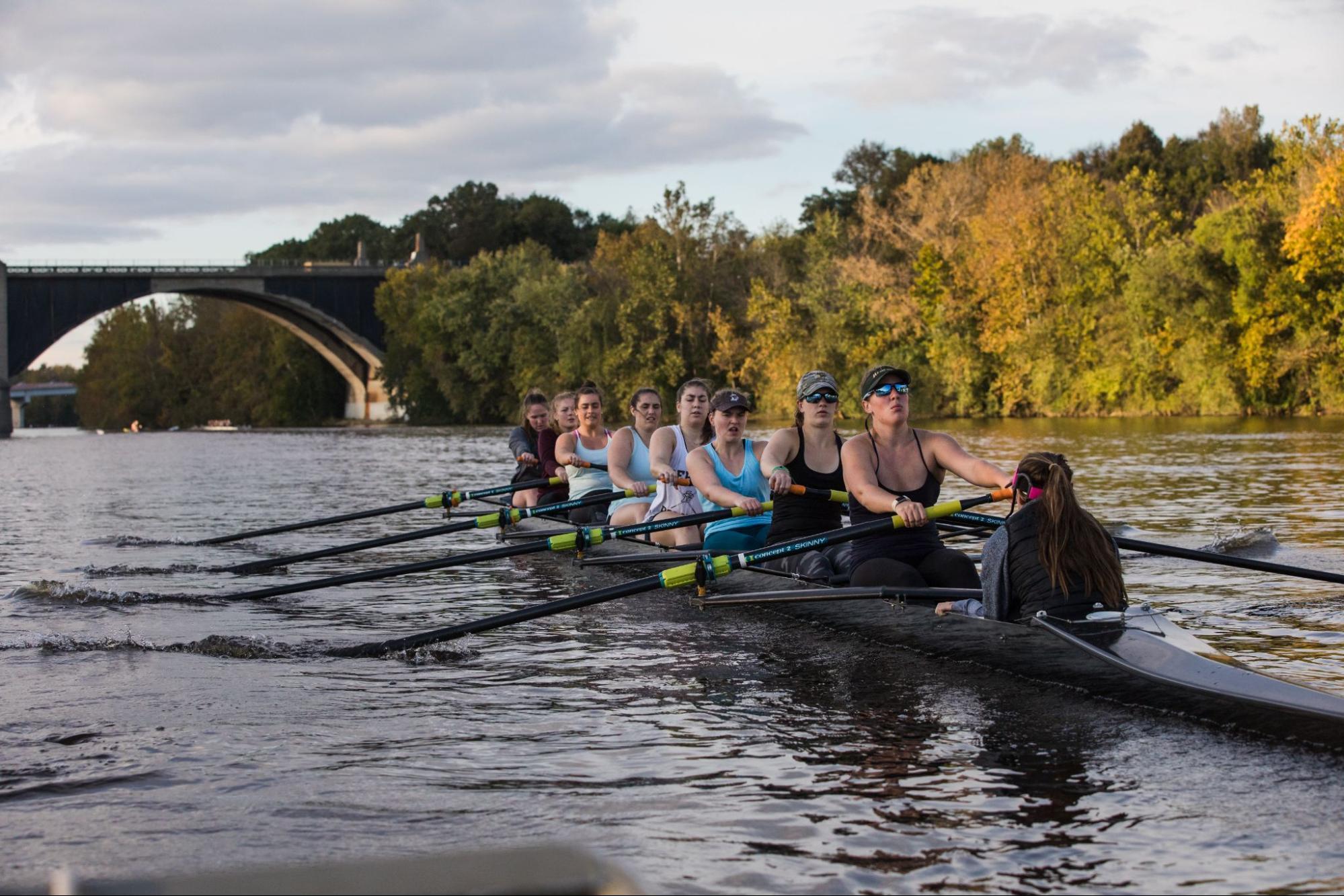 A group of nine women rowing a long boat