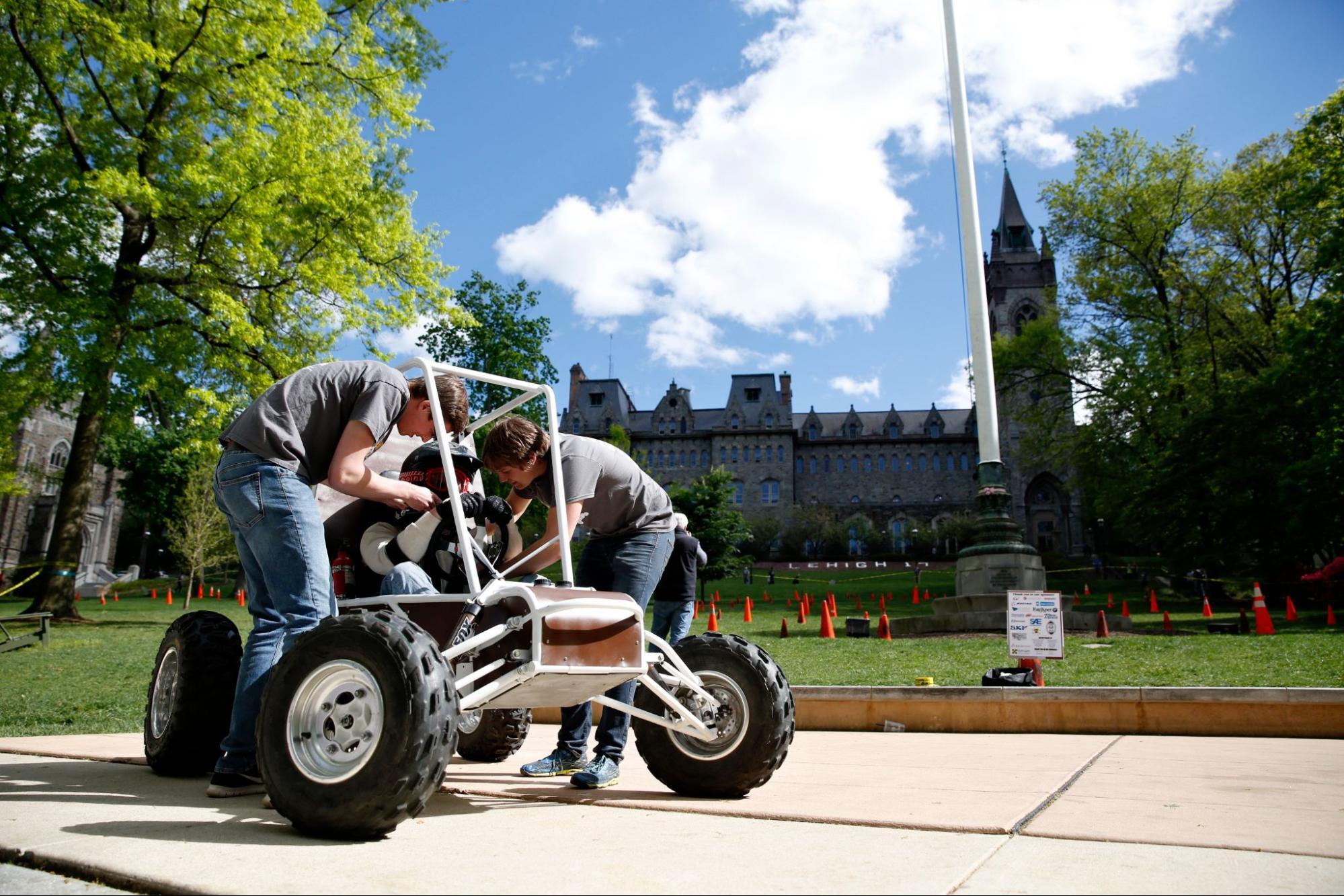 Students working on a car in front of the University Center lawn