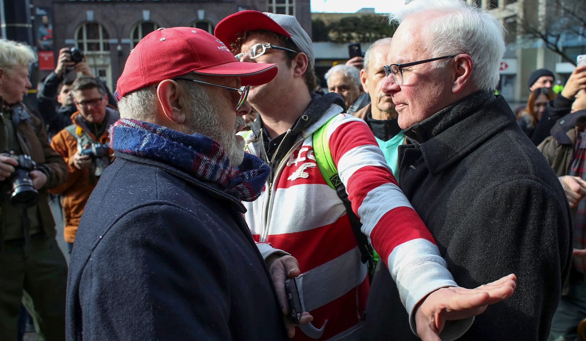 man intervenes in protest between two people from opposing sides