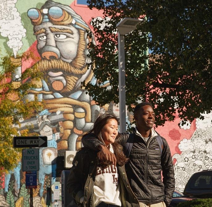 Two people in front of a mural