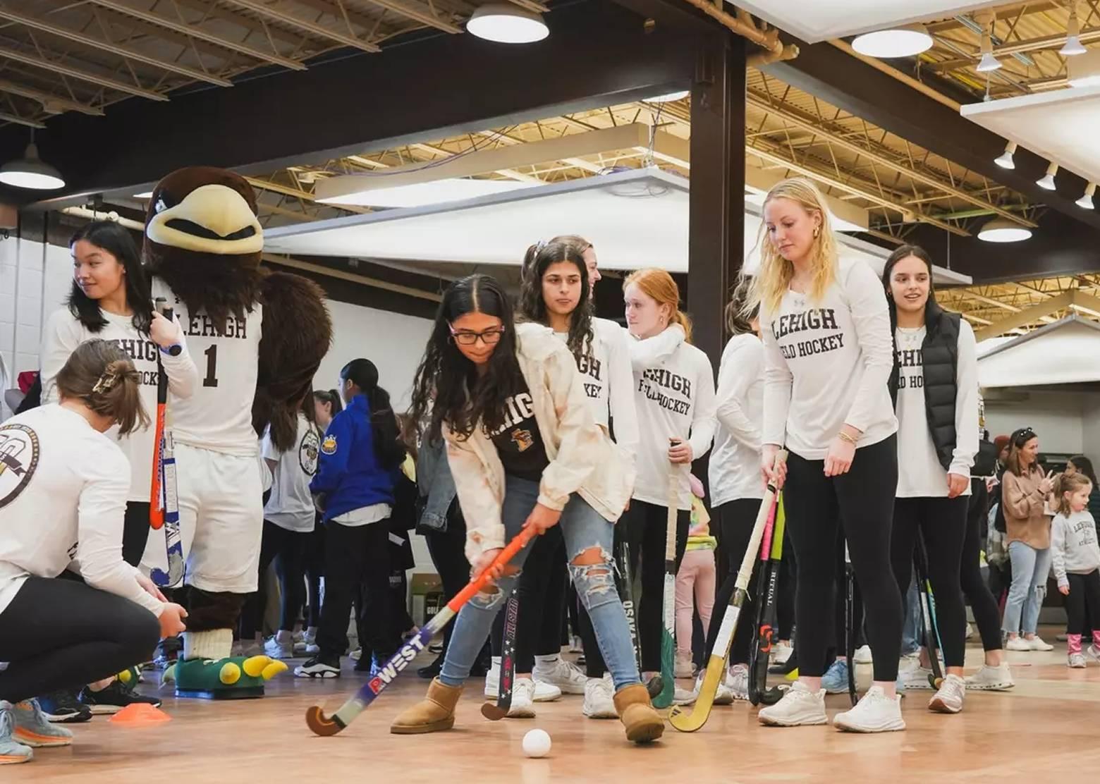 Girls playing indoor field hockey
