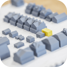 Architectural model with grey houses and one bright yellow house.