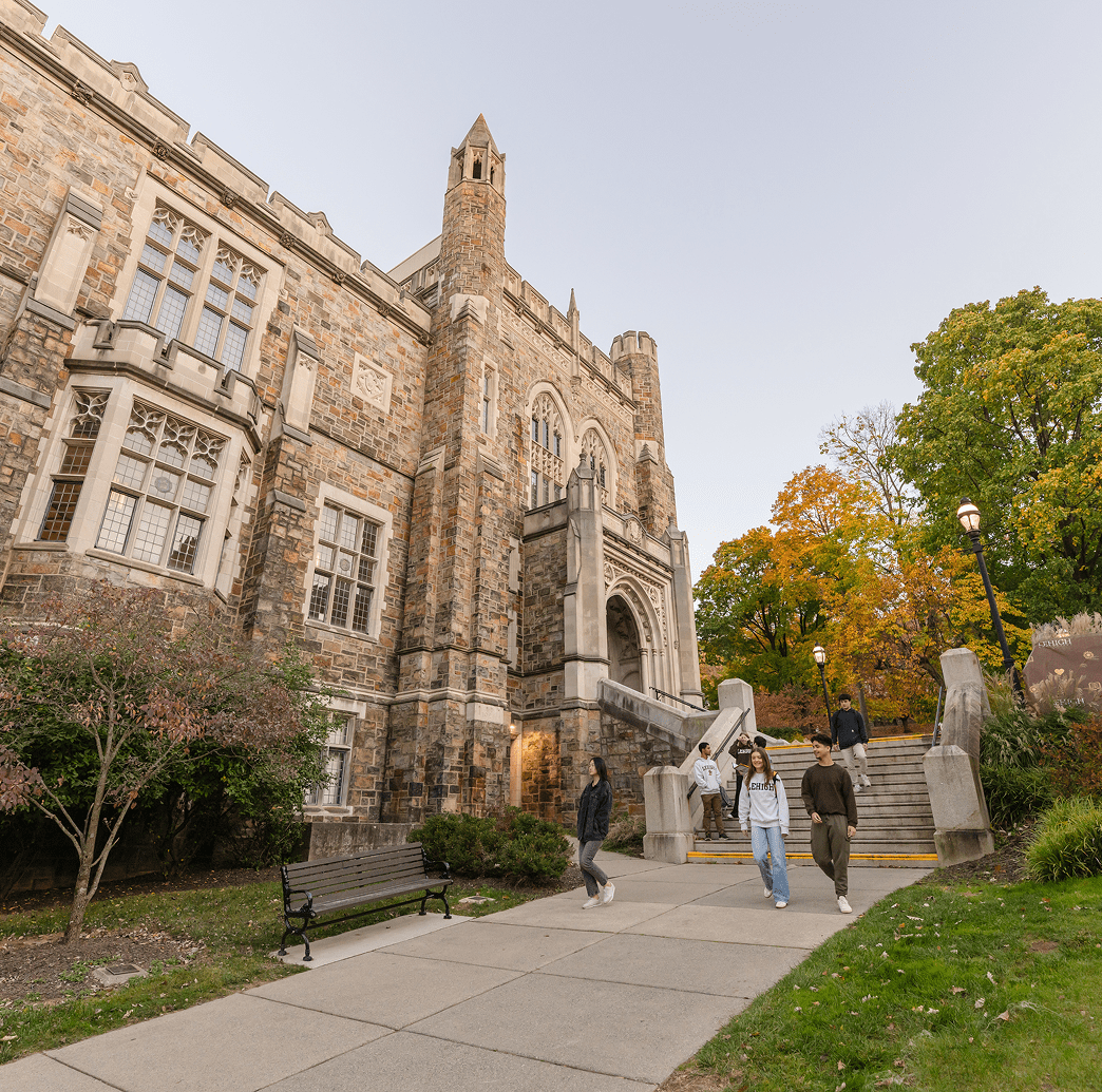 Stone university building with students walking up stairs in autumn.