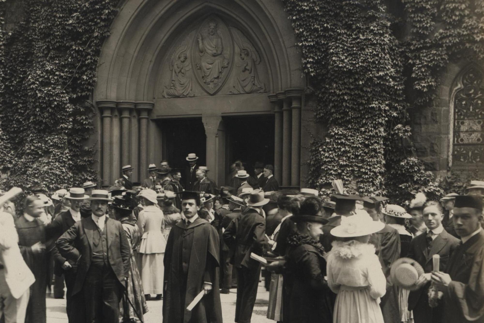 Old photo of people standing outside of an academic building