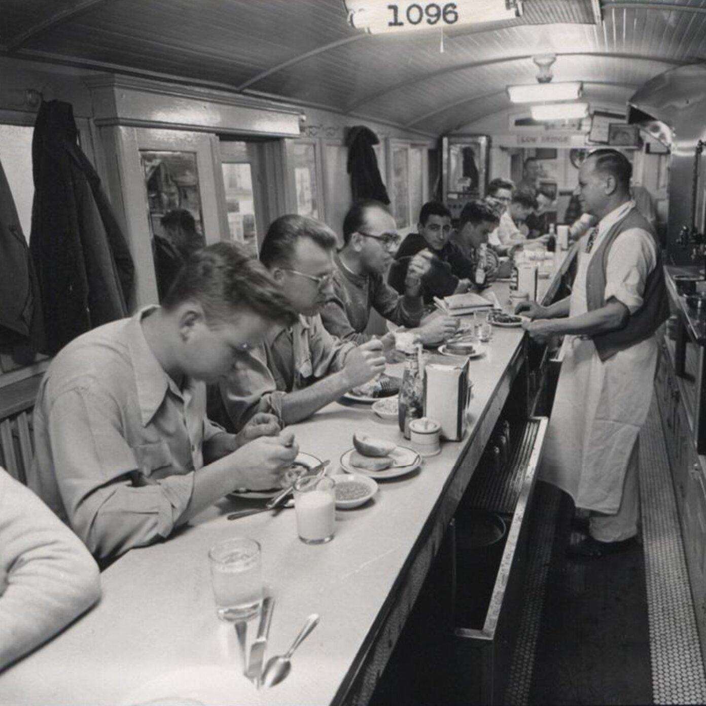 Old black and white photo of people eating in a restaurant