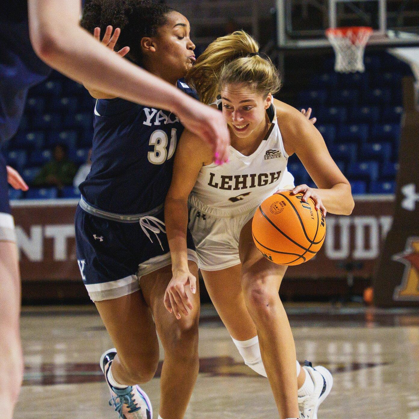 A woman dribbling against a defender during a basketball game
