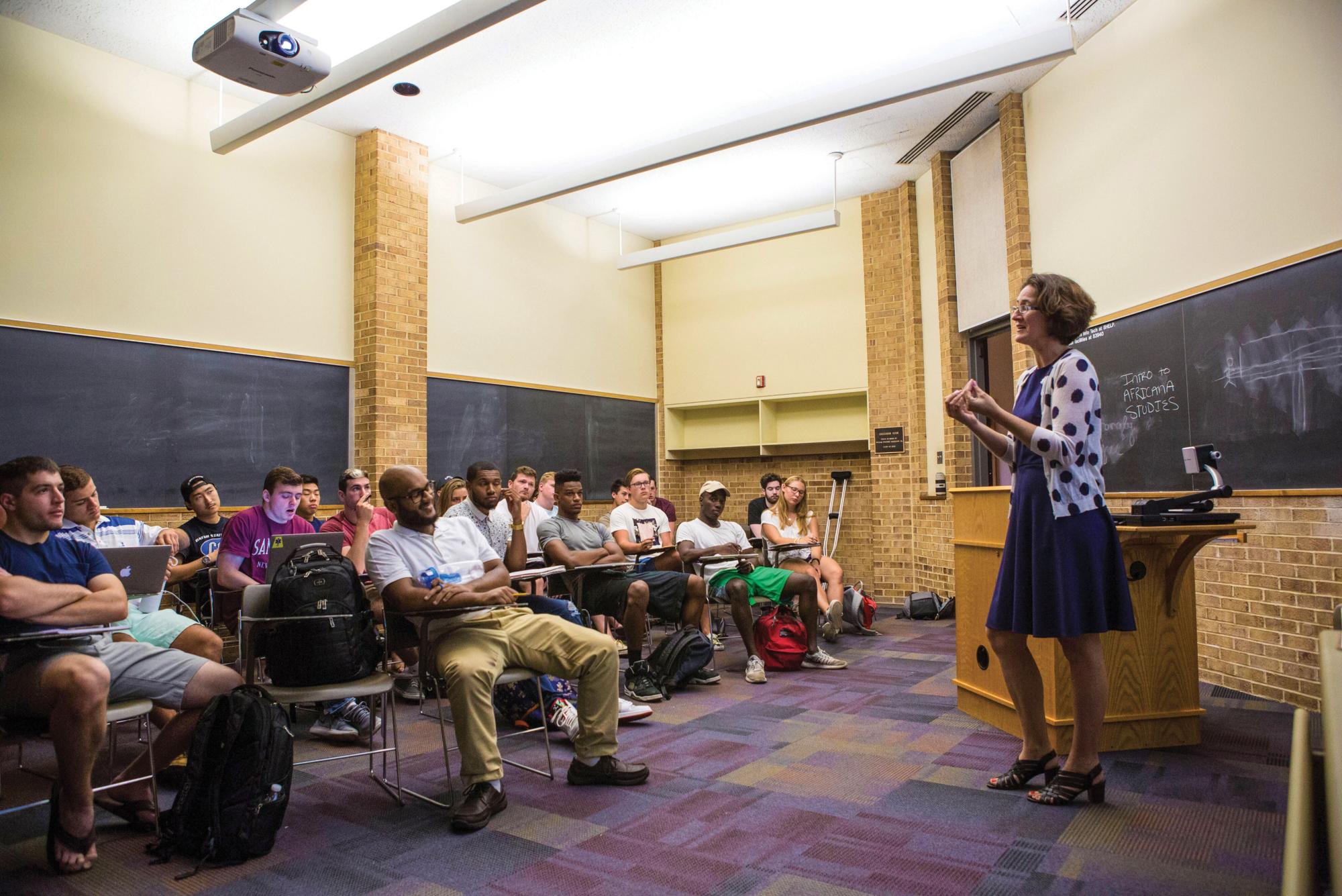 A college classroom, with a professor in front of students seated at desks