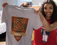 Student holding a shirt with the Umoja crest