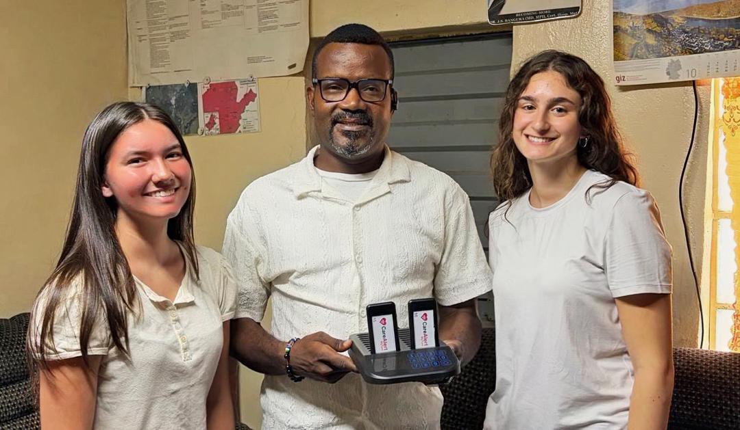 Photograph of three people smiling while holding a dual-screen mobile device.