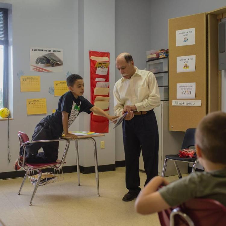 Professor leading a class next to a student at a desk