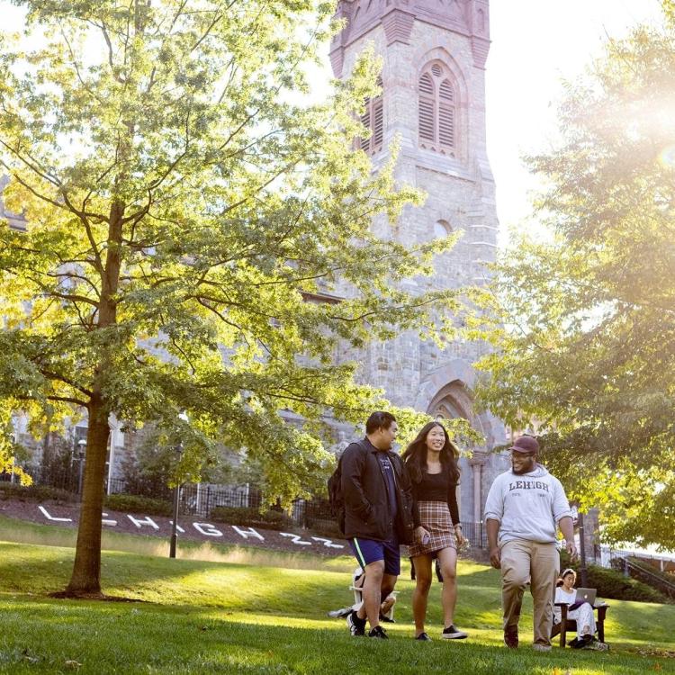 Students walking on a greenway with a building in the background