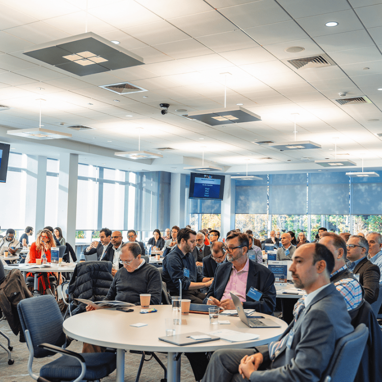 A diverse group of people attend a conference in a brightly lit room.