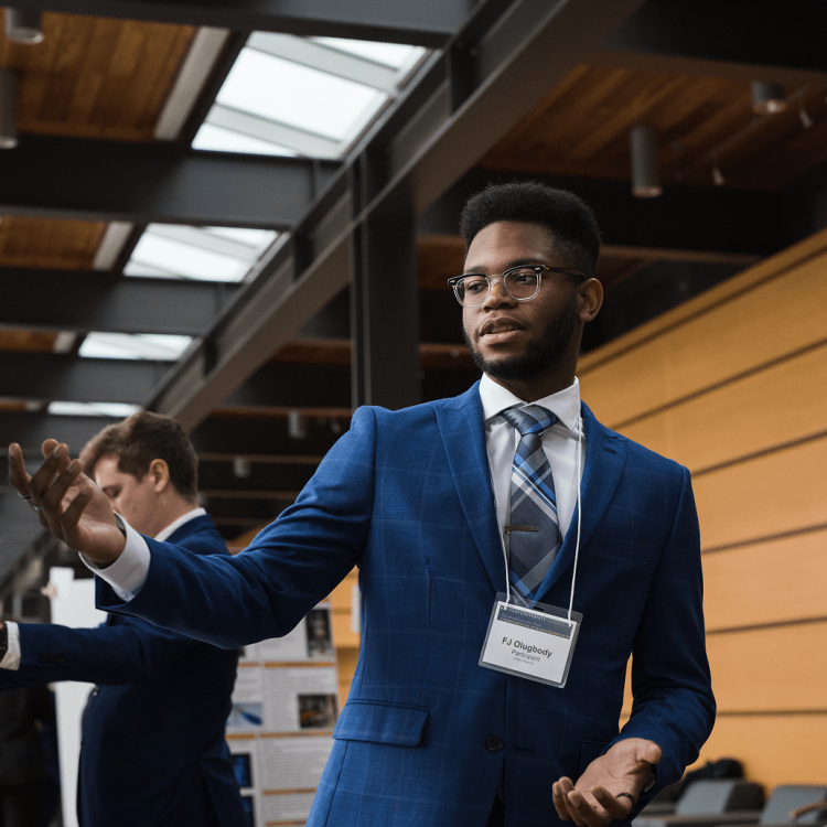 Young Black man in a blue suit gestures while presenting