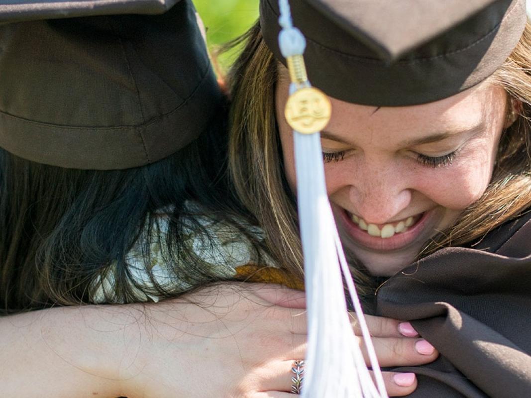 Two graduates hugging at Commencement