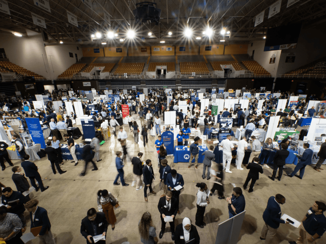 A large indoor career fair with many attendees and booths.