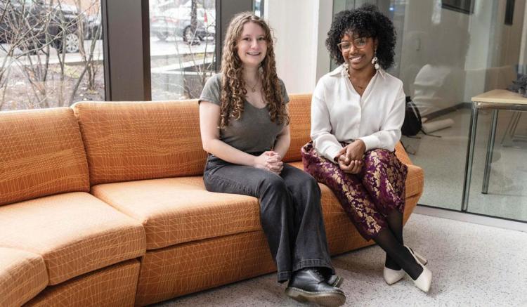 Julie Wright ’25 M’26 and Rhema Hooper ’26 sit on an orange couch in the Health, Science and Technology building.