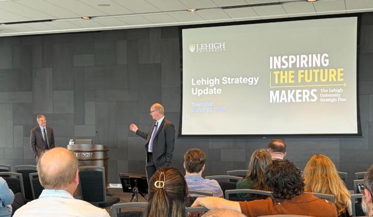 Speaker presenting 'Lehigh Strategy Update' to an audience in a conference hall.