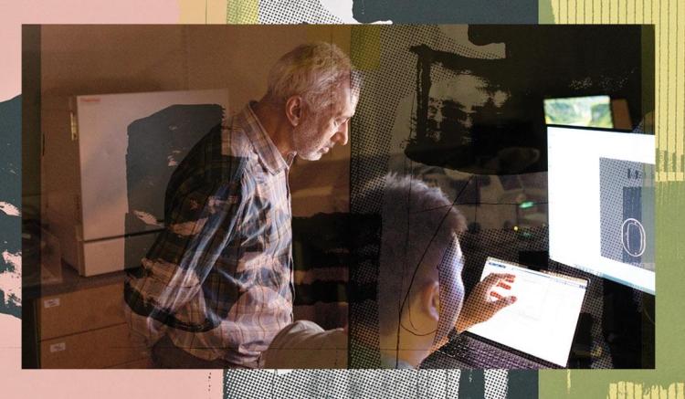 Photograph of two people working together at computer screens in a dark office.